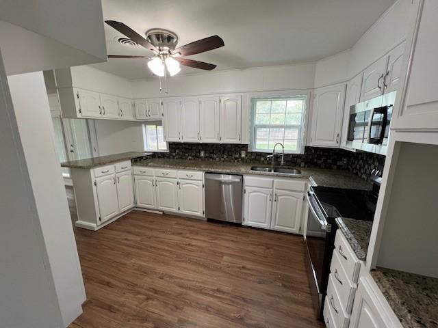 kitchen featuring sink, appliances with stainless steel finishes, white cabinetry, backsplash, and a wealth of natural light