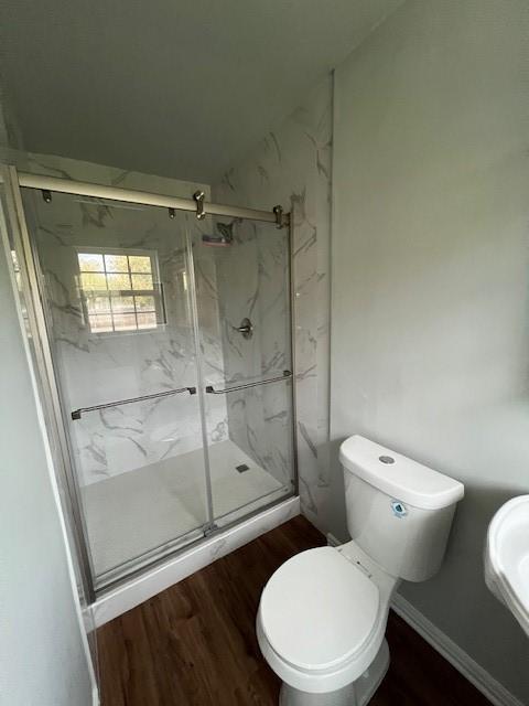 bathroom featuring a shower with door, hardwood / wood-style flooring, sink, and toilet