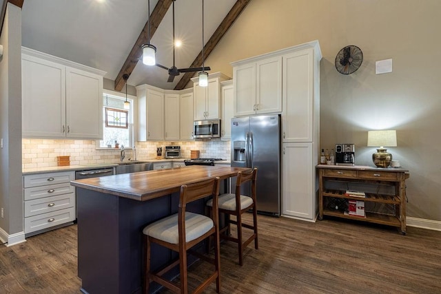 kitchen with stainless steel appliances, dark wood-type flooring, beam ceiling, pendant lighting, and white cabinetry