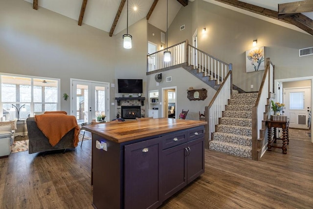 kitchen with pendant lighting, a center island, high vaulted ceiling, and wooden counters