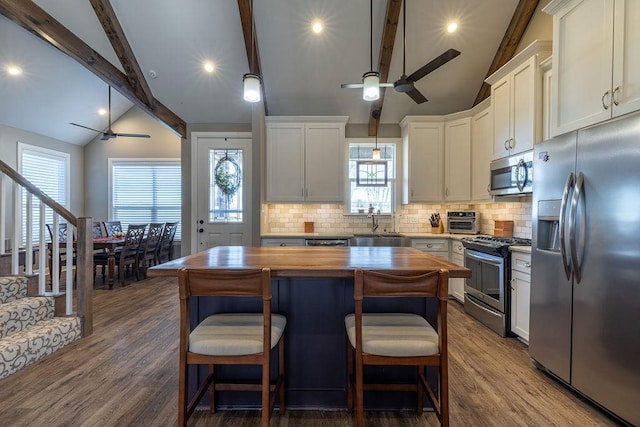 kitchen with butcher block counters, white cabinets, backsplash, a kitchen island, and appliances with stainless steel finishes