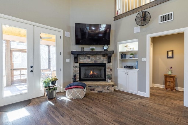 living room with a fireplace, french doors, dark wood-type flooring, and built in shelves