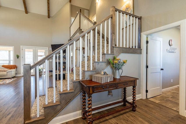 staircase with beam ceiling, wood-type flooring, high vaulted ceiling, and french doors