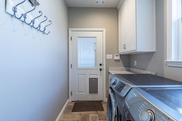 clothes washing area featuring washer and dryer and cabinets