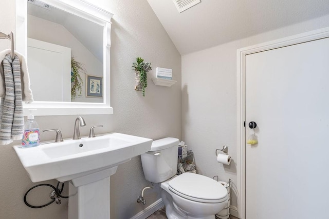 bathroom with toilet, sink, and vaulted ceiling