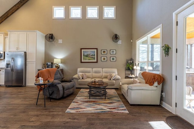 living room with beam ceiling, a towering ceiling, and dark hardwood / wood-style floors