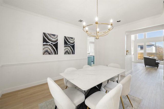 dining space with light wood-type flooring, a notable chandelier, and crown molding