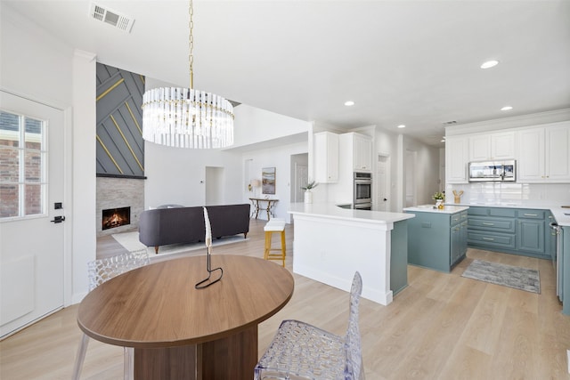 dining area with light hardwood / wood-style floors, ornamental molding, and a chandelier