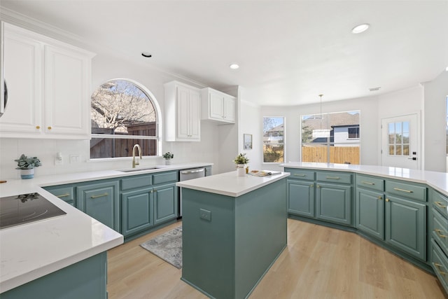 kitchen featuring white cabinets, a kitchen island, sink, hanging light fixtures, and light hardwood / wood-style flooring