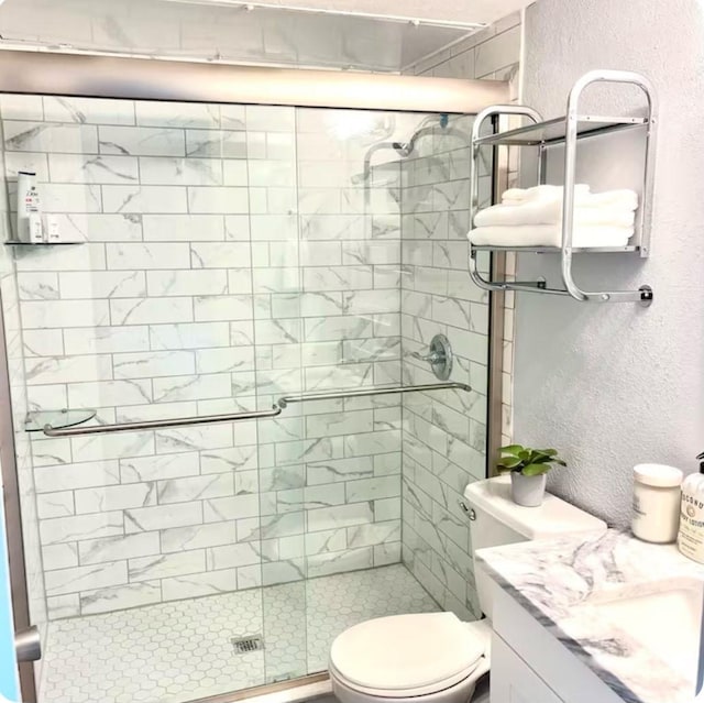 bathroom featuring vanity, walk in shower, and toilet