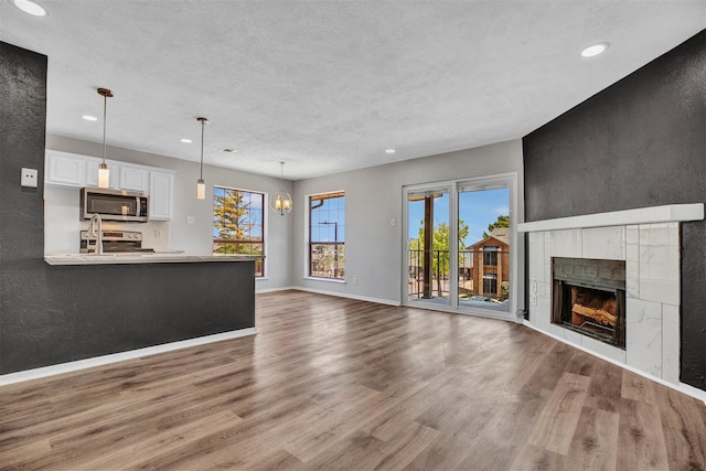 unfurnished living room with a tile fireplace, a wealth of natural light, and hardwood / wood-style floors