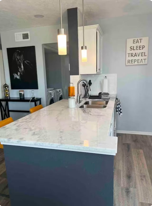 kitchen with dark wood-type flooring, sink, pendant lighting, independent washer and dryer, and white cabinets