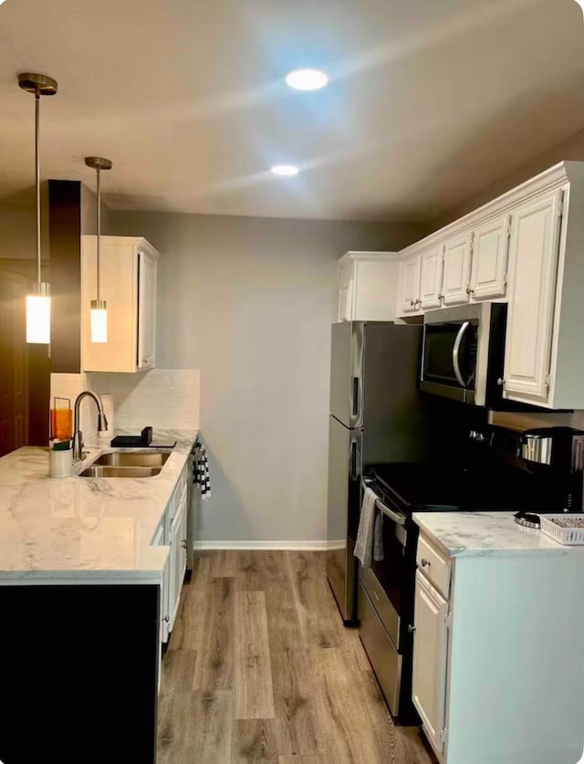 kitchen with sink, range with electric stovetop, pendant lighting, light hardwood / wood-style floors, and white cabinets