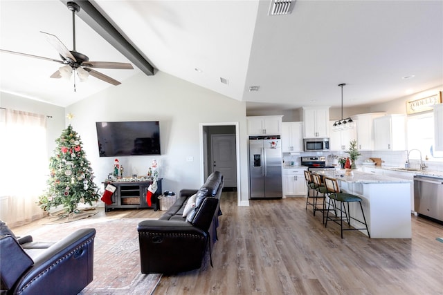 living room featuring ceiling fan, a healthy amount of sunlight, light wood-type flooring, and sink