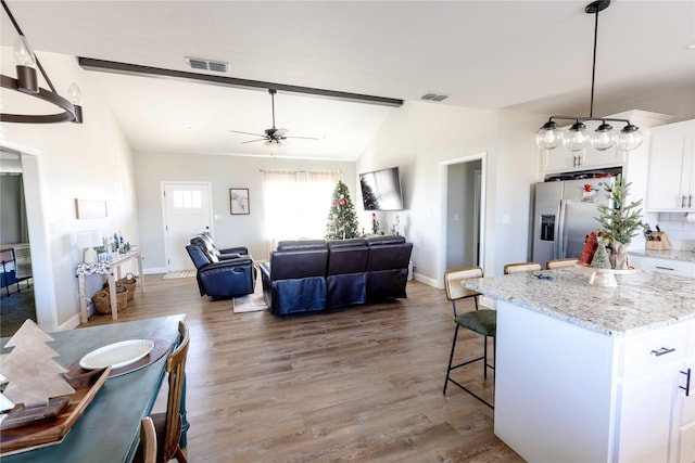 kitchen featuring white cabinetry, stainless steel fridge with ice dispenser, dark hardwood / wood-style flooring, pendant lighting, and a kitchen island