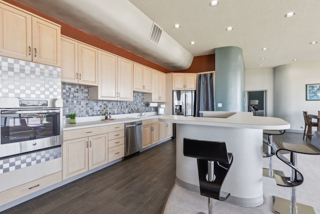 kitchen with tasteful backsplash, a breakfast bar, stainless steel appliances, dark hardwood / wood-style floors, and a kitchen island