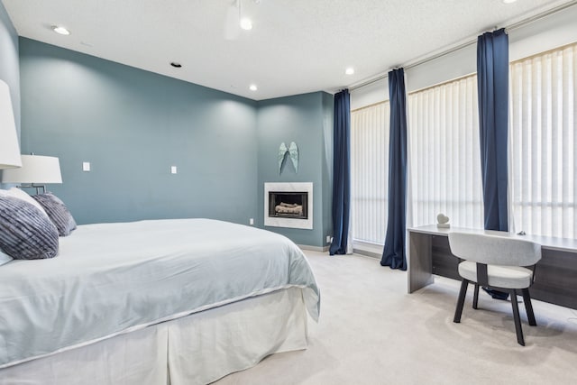 bedroom featuring light colored carpet, a textured ceiling, and a high end fireplace