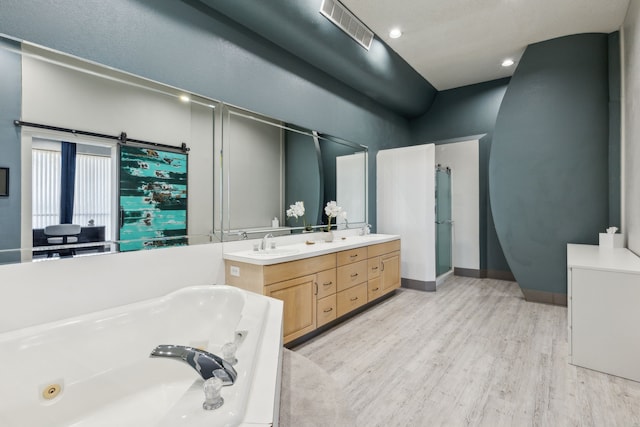 bathroom featuring hardwood / wood-style floors, vanity, and a tub to relax in