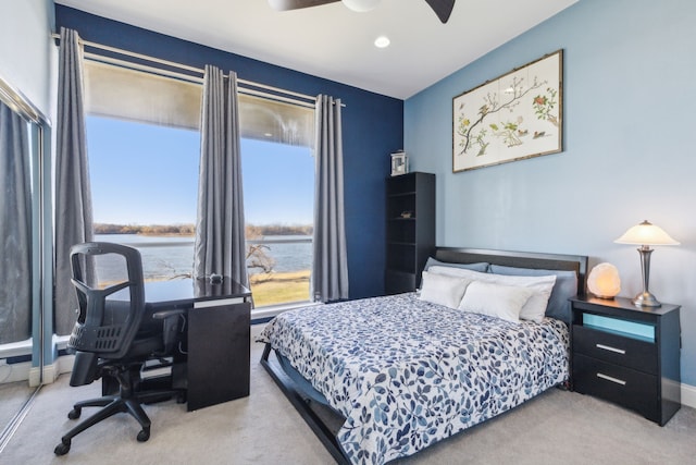 carpeted bedroom with ceiling fan and a water view