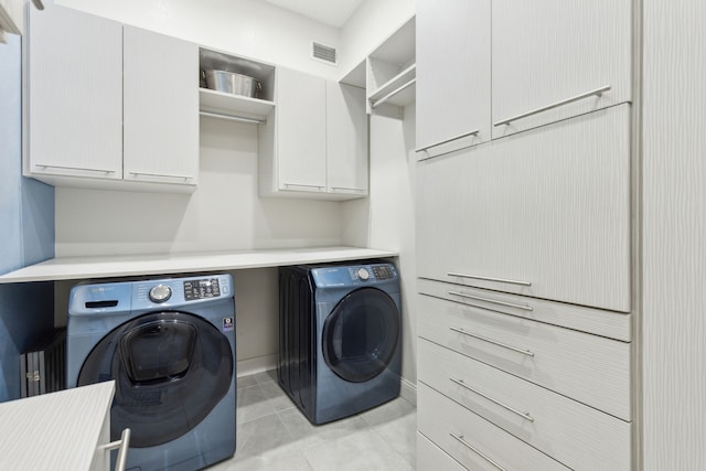 laundry area featuring cabinets, separate washer and dryer, and light tile patterned flooring