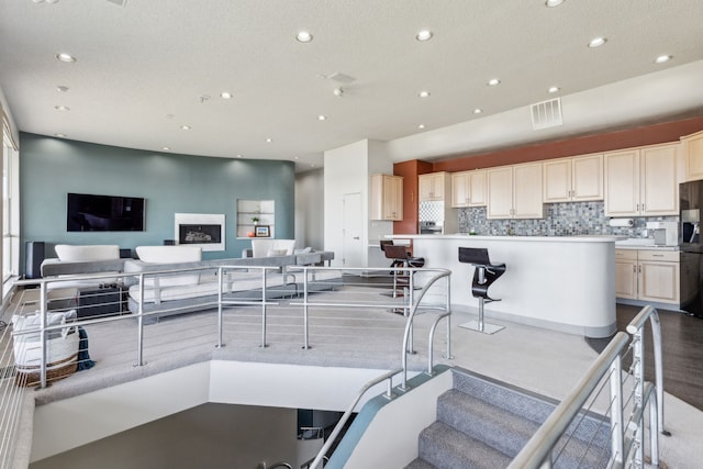 kitchen with decorative backsplash, a breakfast bar, a kitchen island, and refrigerator with ice dispenser