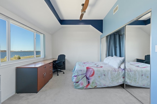 bedroom featuring light carpet, a water view, a closet, and lofted ceiling