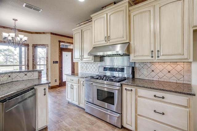 kitchen with cream cabinetry, appliances with stainless steel finishes, and pendant lighting