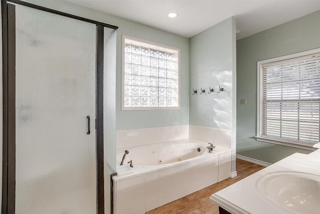 bathroom featuring plus walk in shower, vanity, and hardwood / wood-style flooring