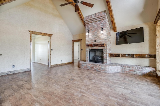 unfurnished living room featuring ceiling fan, beamed ceiling, high vaulted ceiling, and a brick fireplace