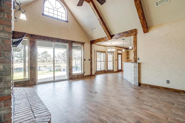 unfurnished living room featuring beamed ceiling, ceiling fan with notable chandelier, and a towering ceiling