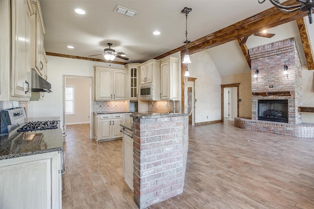 kitchen featuring stainless steel microwave, backsplash, hanging light fixtures, ceiling fan, and cream cabinetry