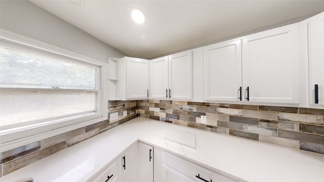 kitchen featuring white cabinets, backsplash, and light stone counters