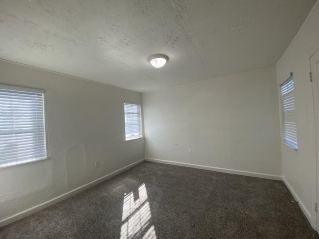 spare room with dark carpet and a textured ceiling