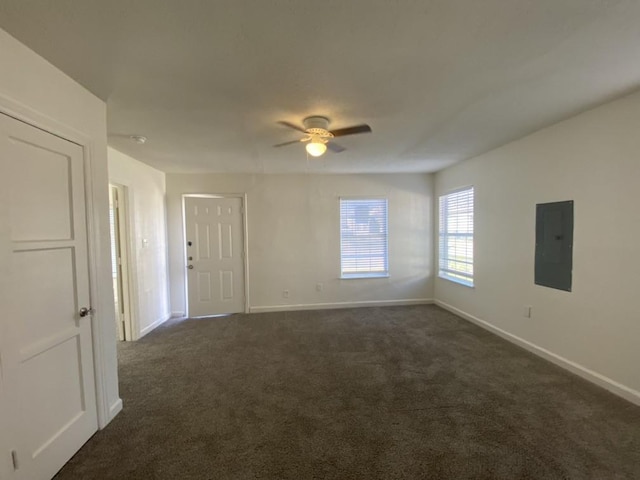 empty room with electric panel, ceiling fan, and dark colored carpet