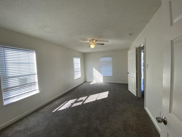 spare room featuring ceiling fan, dark carpet, and a textured ceiling