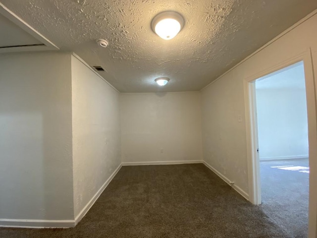 basement featuring dark carpet and a textured ceiling