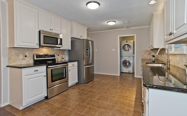 kitchen with sink, crown molding, white cabinetry, stainless steel appliances, and stacked washer and clothes dryer