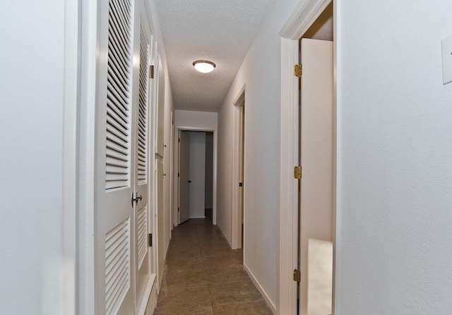 corridor featuring tile patterned floors and a textured ceiling