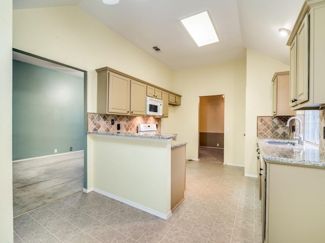 kitchen with decorative backsplash, light stone countertops, lofted ceiling, and sink