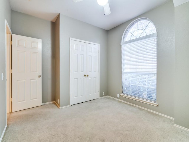 unfurnished bedroom featuring ceiling fan, a closet, and light colored carpet