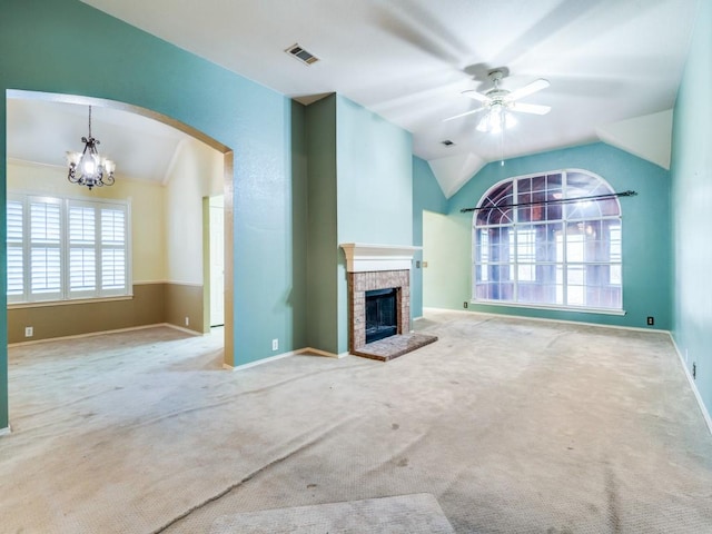 unfurnished living room with carpet, ceiling fan with notable chandelier, a brick fireplace, and lofted ceiling