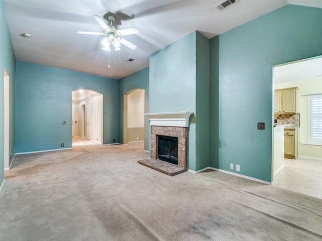 unfurnished living room featuring light carpet, a brick fireplace, and ceiling fan