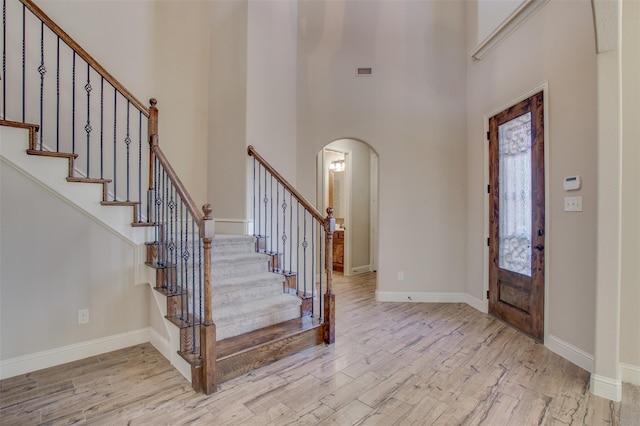 entryway featuring light hardwood / wood-style floors and a towering ceiling