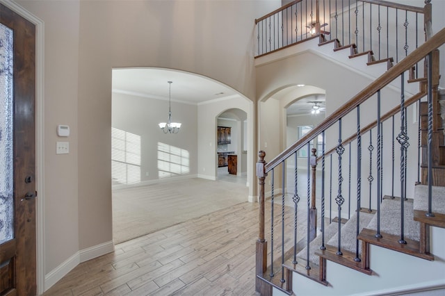 foyer entrance featuring crown molding, a high ceiling, and ceiling fan with notable chandelier