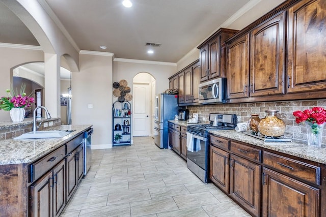 kitchen with dark brown cabinetry, appliances with stainless steel finishes, light stone countertops, and sink