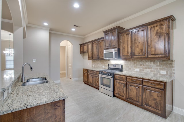 kitchen featuring sink, backsplash, stainless steel appliances, dark brown cabinetry, and light stone countertops