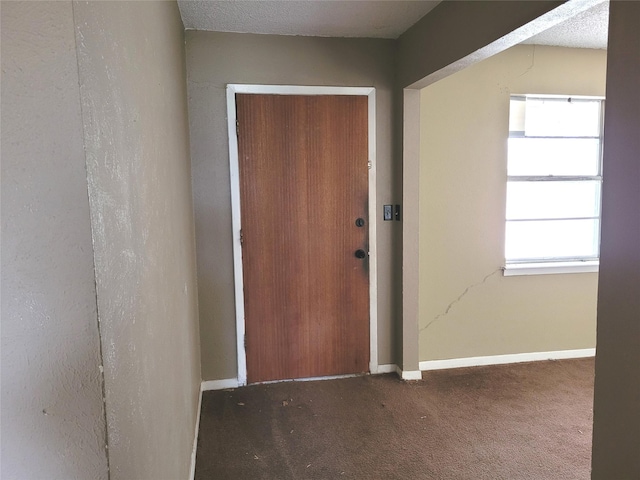 interior space featuring dark colored carpet and a textured ceiling