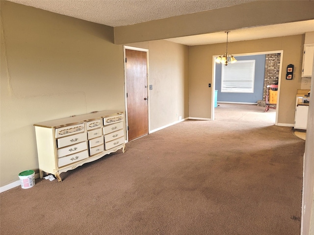 carpeted empty room featuring a textured ceiling and an inviting chandelier