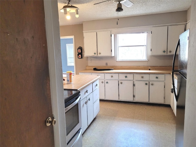 kitchen featuring stove, fridge, a textured ceiling, white cabinetry, and hanging light fixtures