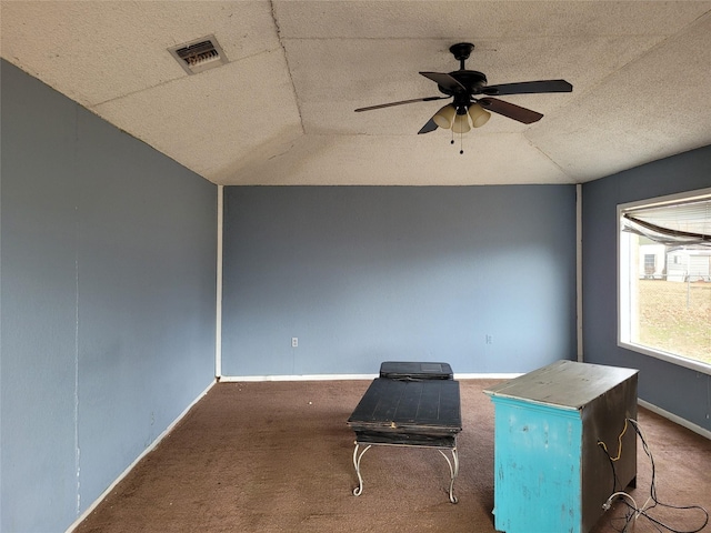 unfurnished room with a textured ceiling, dark carpet, ceiling fan, and lofted ceiling